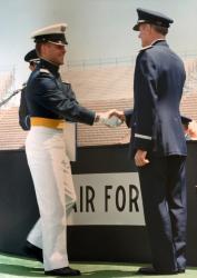 Two military officers in uniform shaking hands at a ceremony.