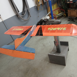 A red and blue model airplane on a stand in a workshop.