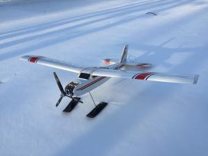 Model airplane with skis rests on snow.
