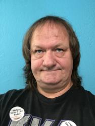 Portrait of a person with shoulder-length hair against a blue background, wearing a black shirt.