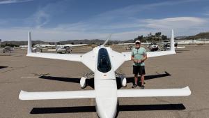 Man standing beside a small white aircraft at an airport.
