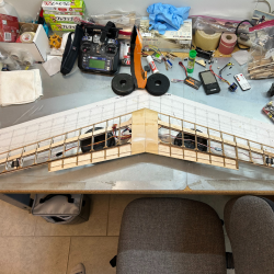 Worktable with a model airplane in construction, tools, and electronics scattered around.