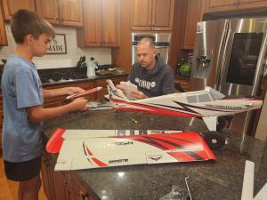 Father and son assembling a model airplane in the kitchen.