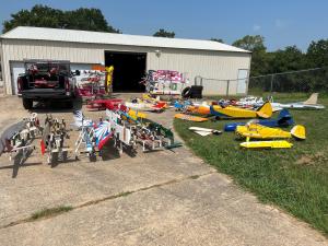 Colorful model airplanes displayed outdoors near a garage on a sunny day.