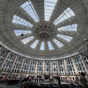 Spacious dome interior with ornate glass ceiling and people below.