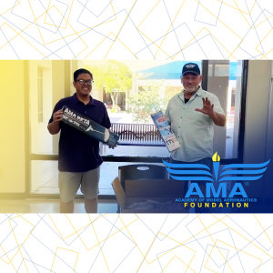 Two people smiling with model aircraft kits, AMA Foundation logo displayed.
