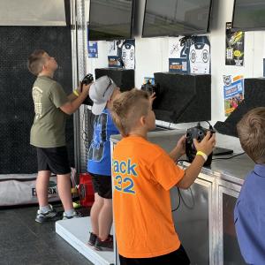 Children playing video games at a display with multiple screens.