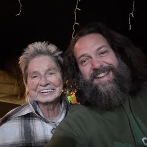 Smiling older woman and bearded man outdoors at night.