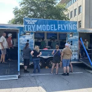 Mobile exhibit with people gathered at model flying event.