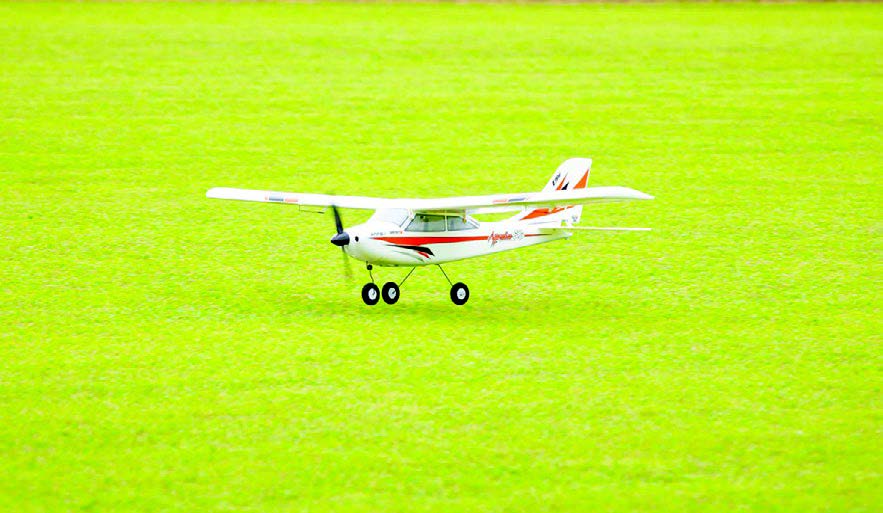 Remote-controlled plane on a grassy field.