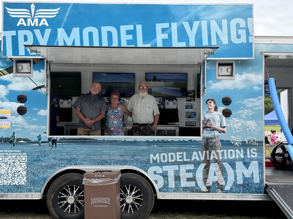 AMA booth with three people smiling, promoting model aviation.